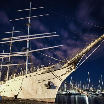 Das Schulschiff Gorch Fock liegt angeleint im Hafen von Stralsund. Der nächtliche Himmel ist durch die Langzeitbelichtung leicht verwischt.