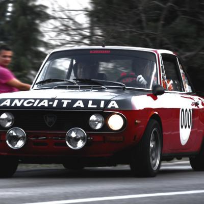 Ein rotes Rallyauto von Lancia bei einem Autorennen.